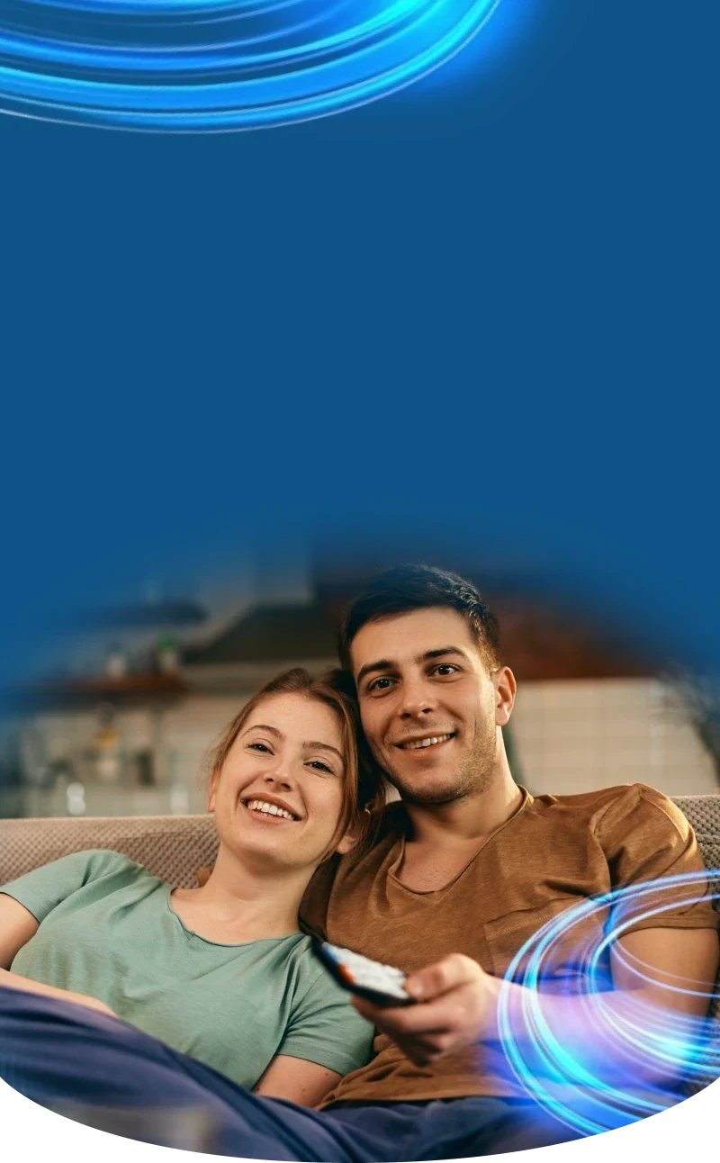Casal sorrindo no sofá da sala, com ondas de luz azul ao fundo